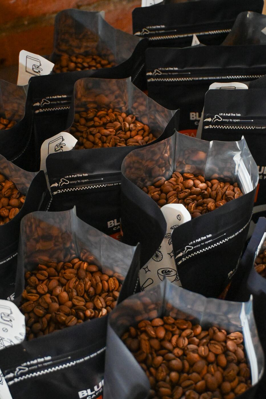Bolsas de café recién tostado llenándose en la casa de tostado Selenia